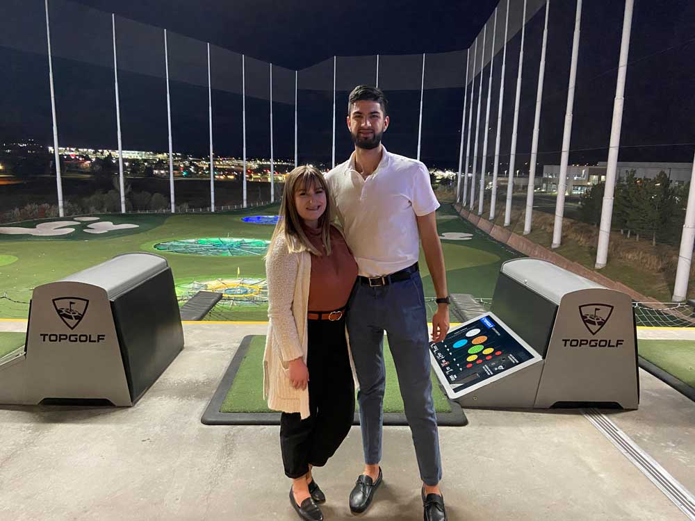 Two individuals from JA Engage standing in front of green at Top Golf